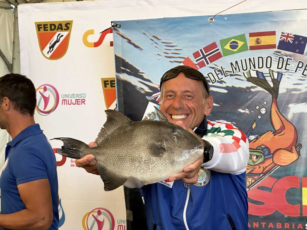 Marco Bardi ai Mondiali 2023 di pesca in apnea in Spagna, scherza cercando di far apparire più grande un pesce balestra